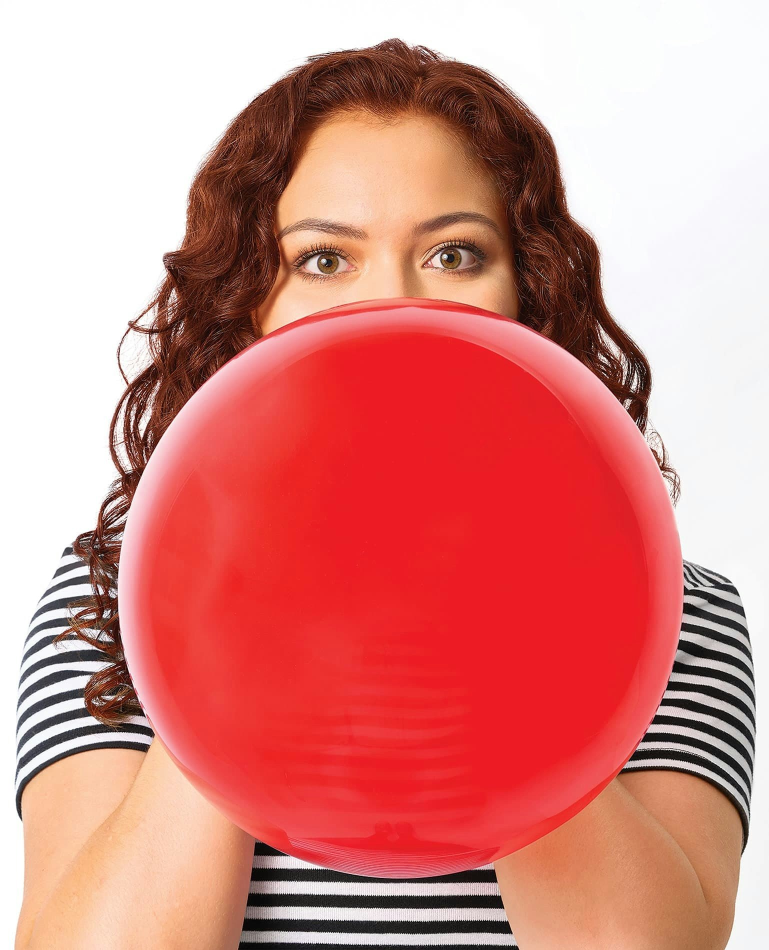 A woman blowing up a red balloon.